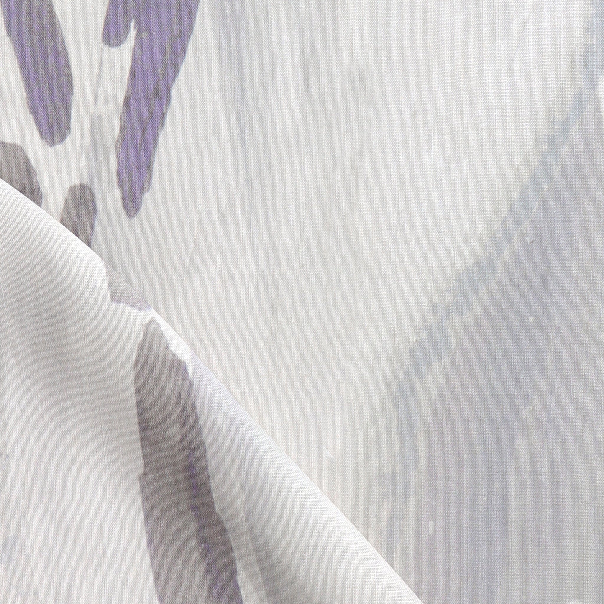 Draped fabric yardage in an abstract paint print in shades of purple and gray on a cream field.