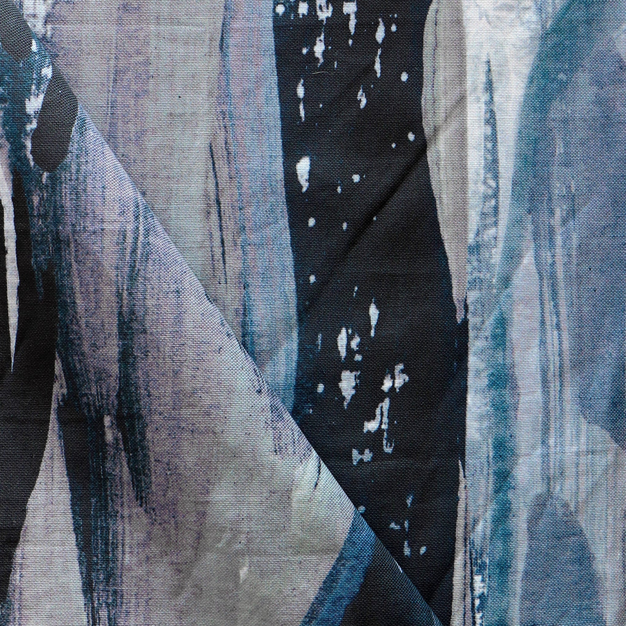 Draped fabric yardage in an abstract paint print in shades of black, purple and blue on a gray field.