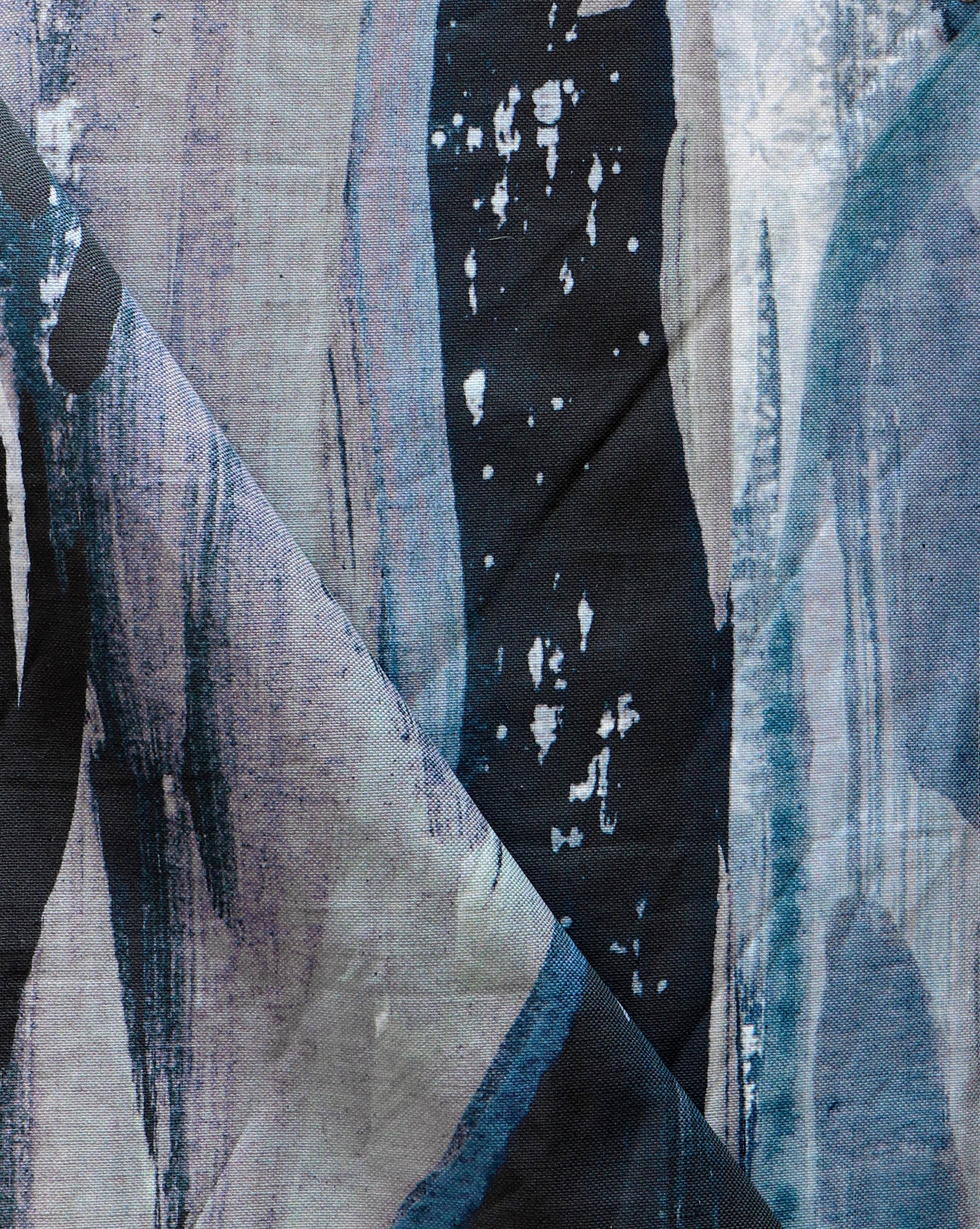 Draped fabric yardage in an abstract paint print in shades of black, purple and blue on a gray field.