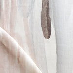 Draped fabric yardage in an abstract paint print in shades of pink, brown and gray on a cream field.