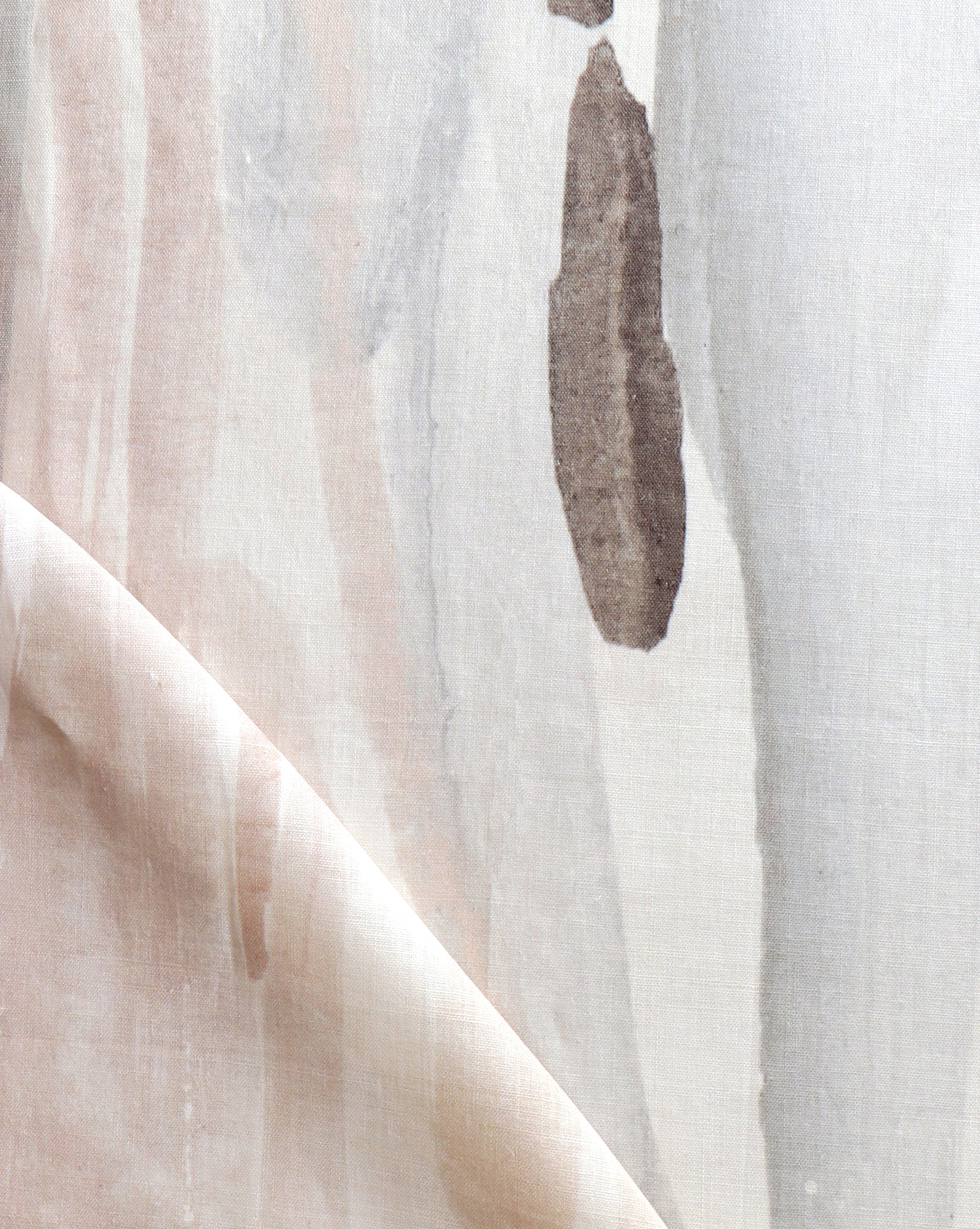 Draped fabric yardage in an abstract paint print in shades of pink, brown and gray on a cream field.