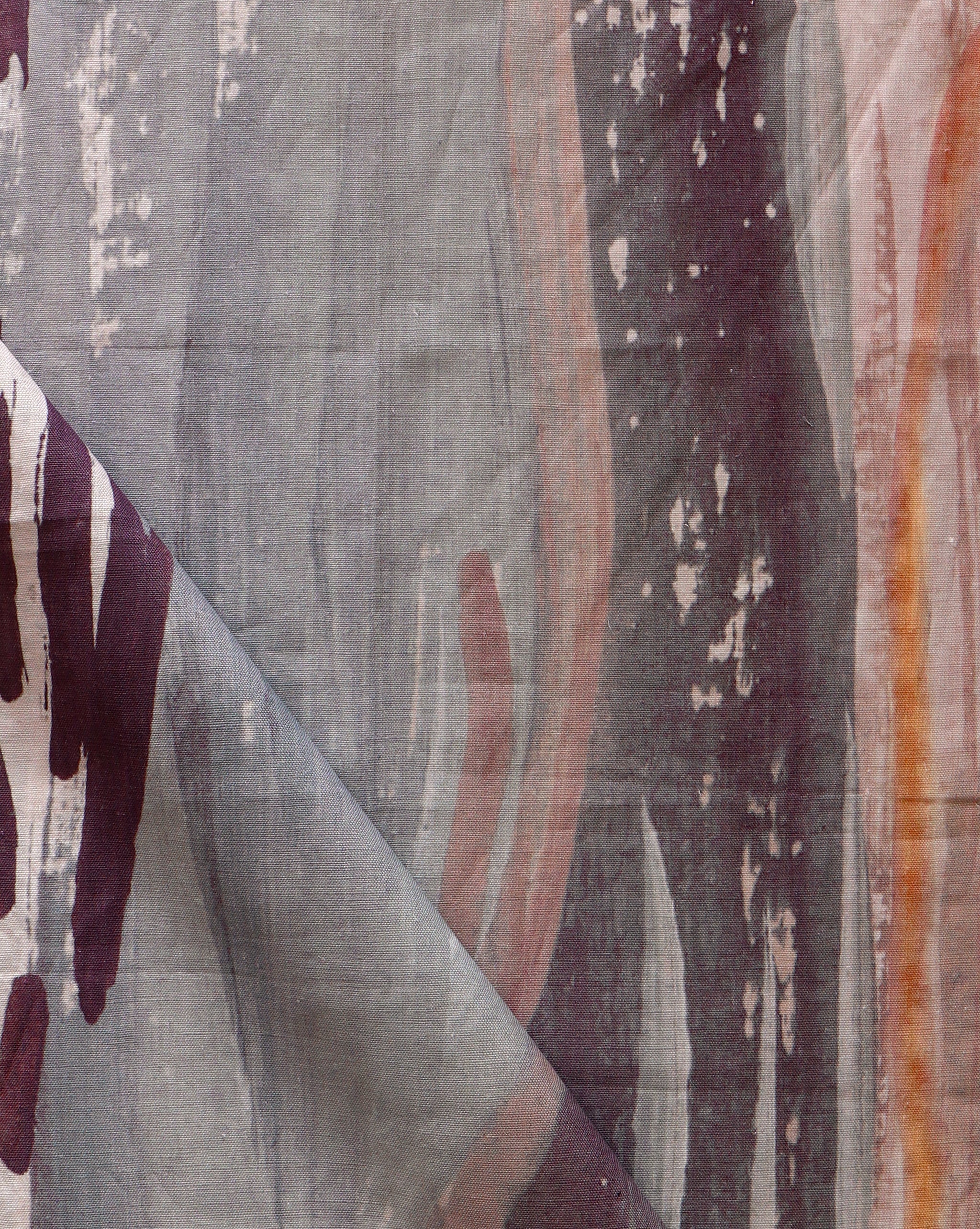 Draped fabric yardage in an abstract paint print in shades of gray, orange and purple on a cream field.