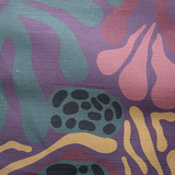 Draped fabric in a playful abstract shape print in shades of yellow, purple, green and black on a purple field.