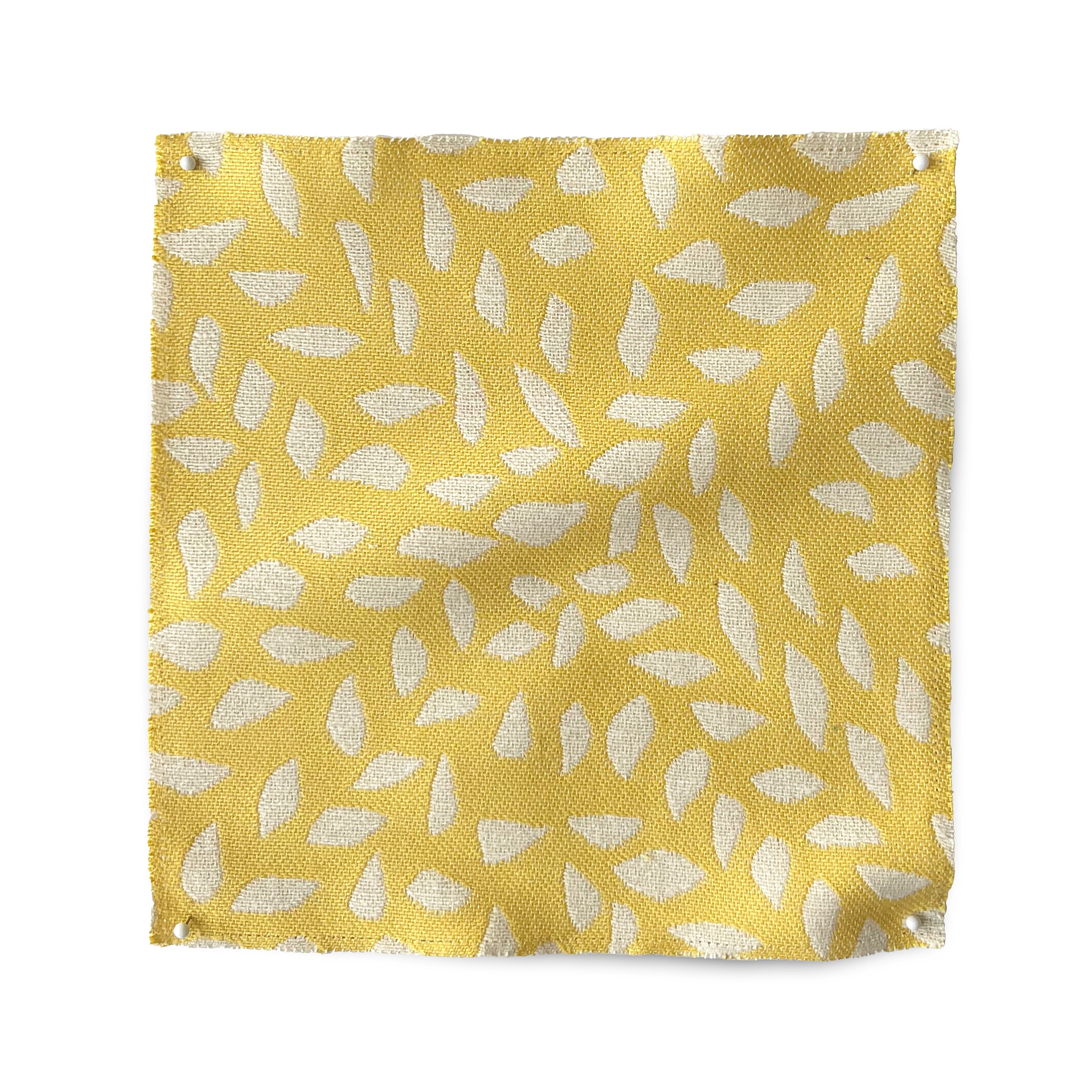 Square fabric swatch in a botanical trellis print in white on a yellow field.