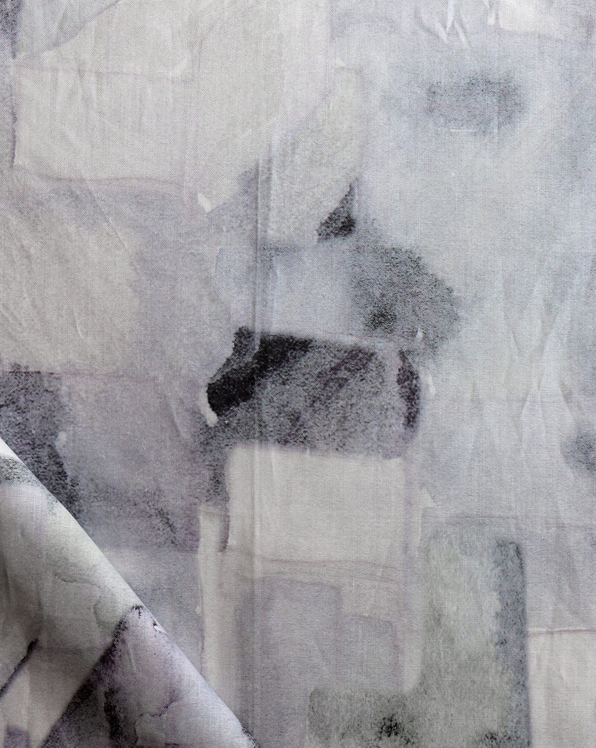 Draped fabric yardage in a textural paint blotch print in shades of gray and blue on a light gray field.