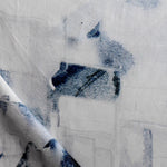 Draped fabric yardage in a textural paint blotch print in shades of black and navy on a white field.