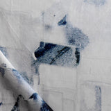 Draped fabric yardage in a textural paint blotch print in shades of black and navy on a white field.