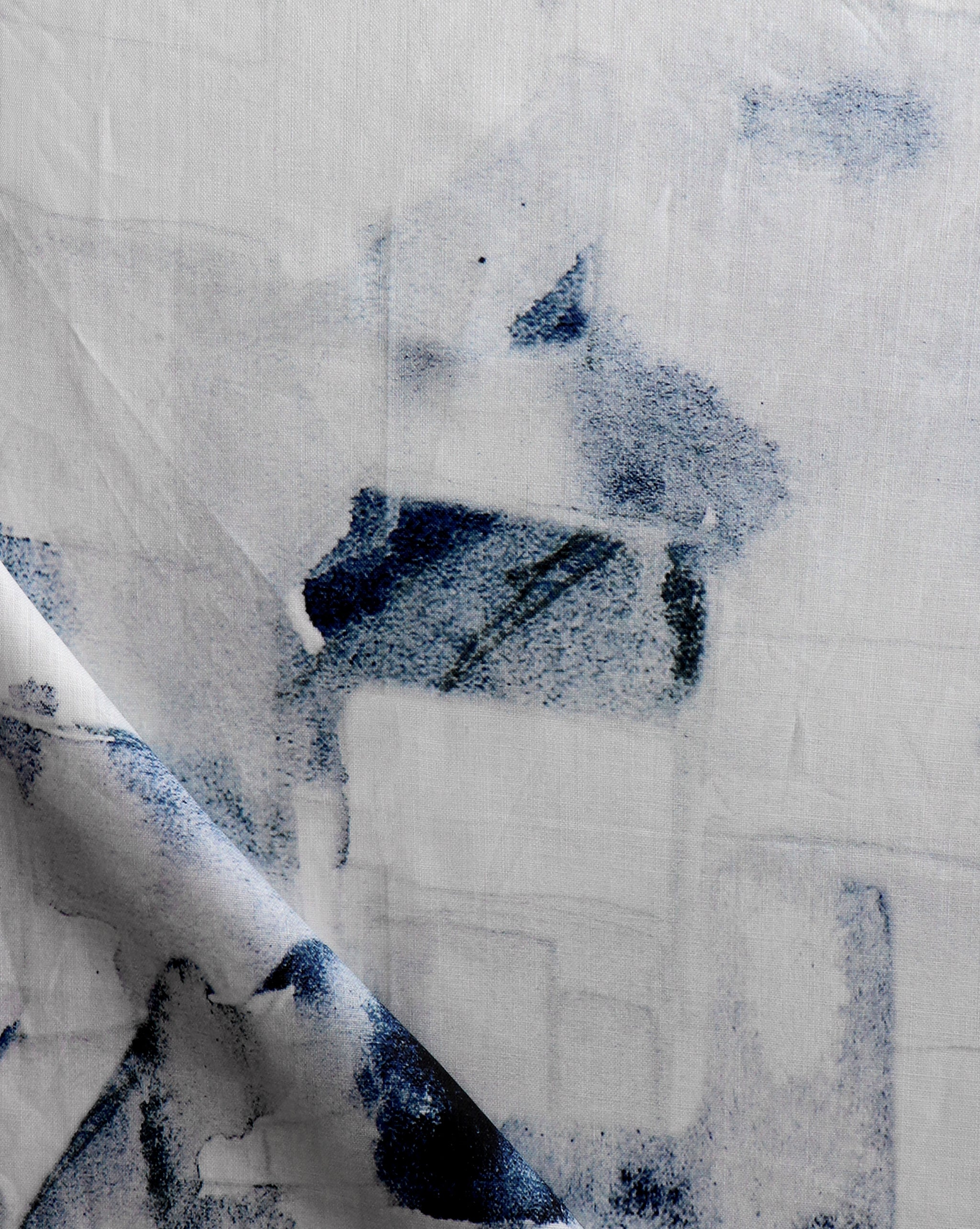 Draped fabric yardage in a textural paint blotch print in shades of black and navy on a white field.