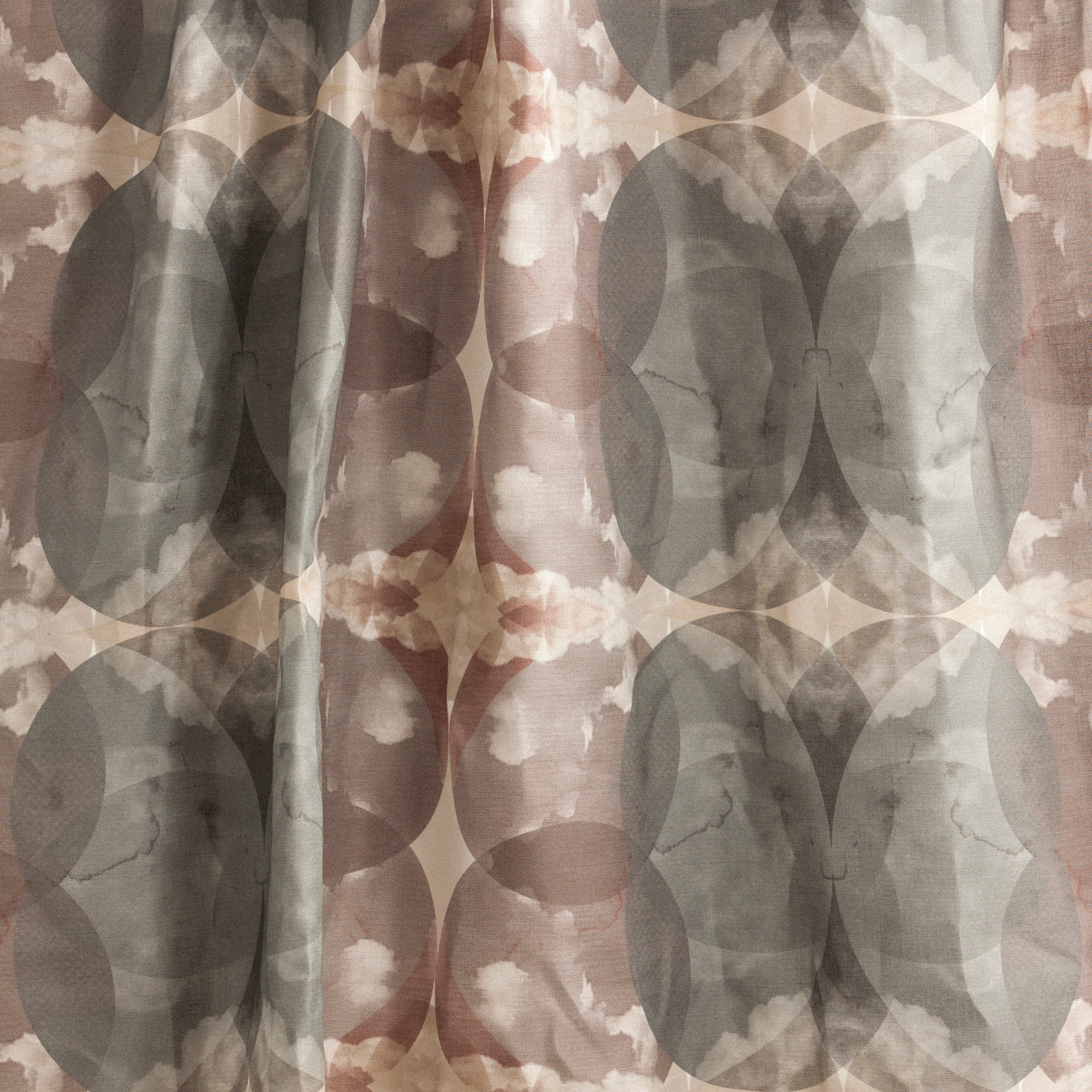 Draped fabric yardage in a cloudy ink blot print in shades of gray and pink on a cream field.