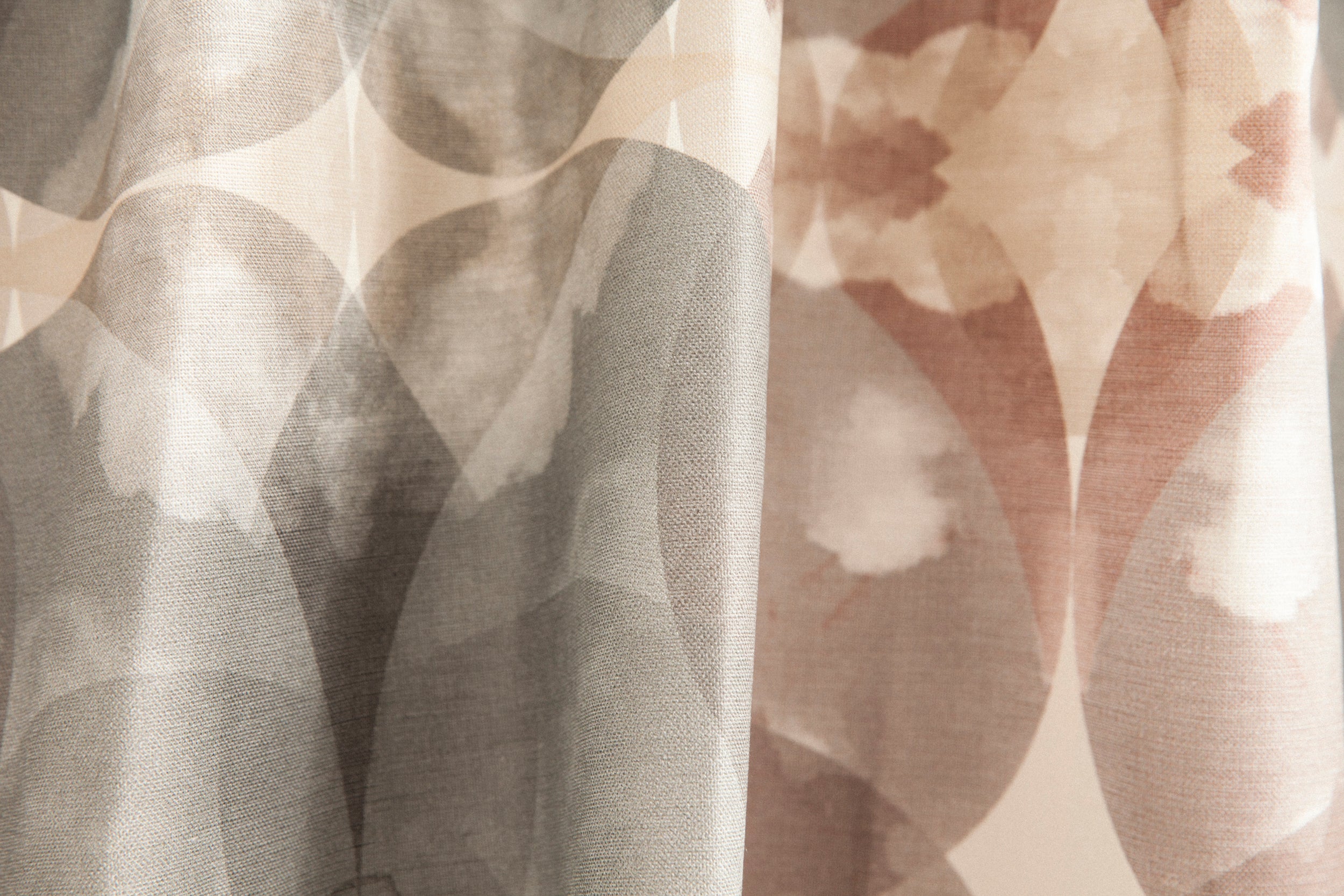 Close-up of draped fabric in a cloudy ink blot print in shades of gray and pink on a cream field.