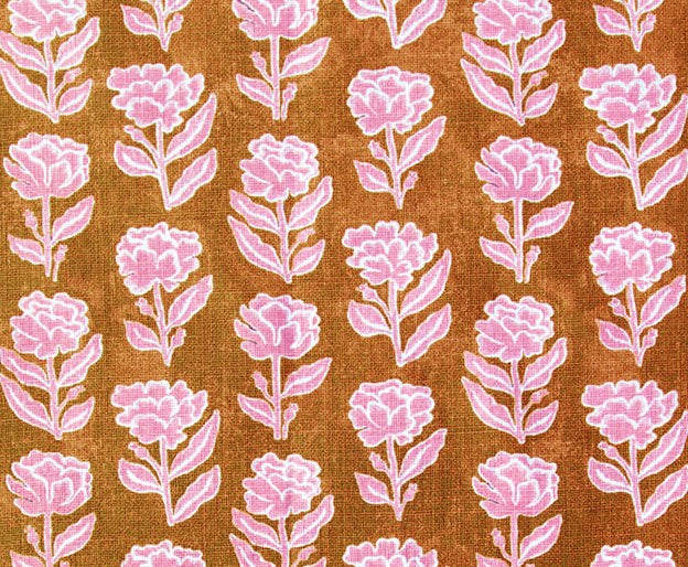 Detail of fabric in a floral grid print in pink and white on a rust field.