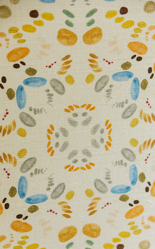 Detail of fabric in a painterly grid print in shades of blue and orange on a cream field.