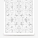 Partially unrolled wallpaper yardage in an abstract ink blot print in gray on a white field.