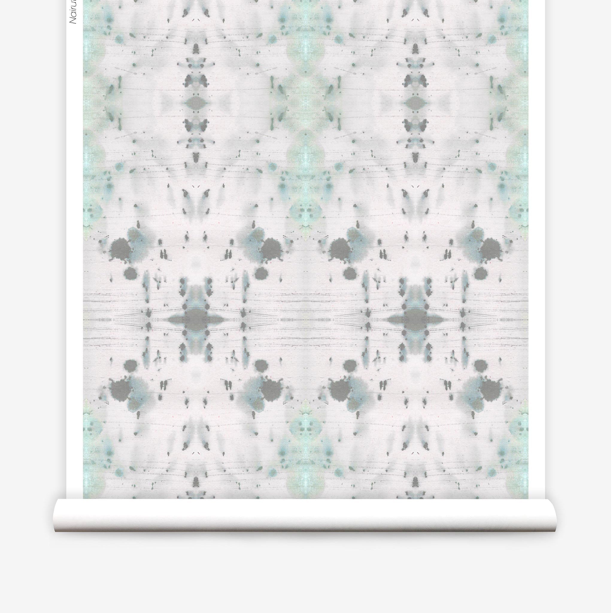 Partially unrolled wallpaper yardage in an abstract ink blot print in gray and green on a cream field.