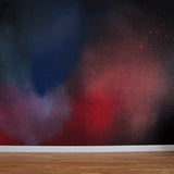 A wall mural in an abstract ombré paint splatter print in shades of red, blue and black.