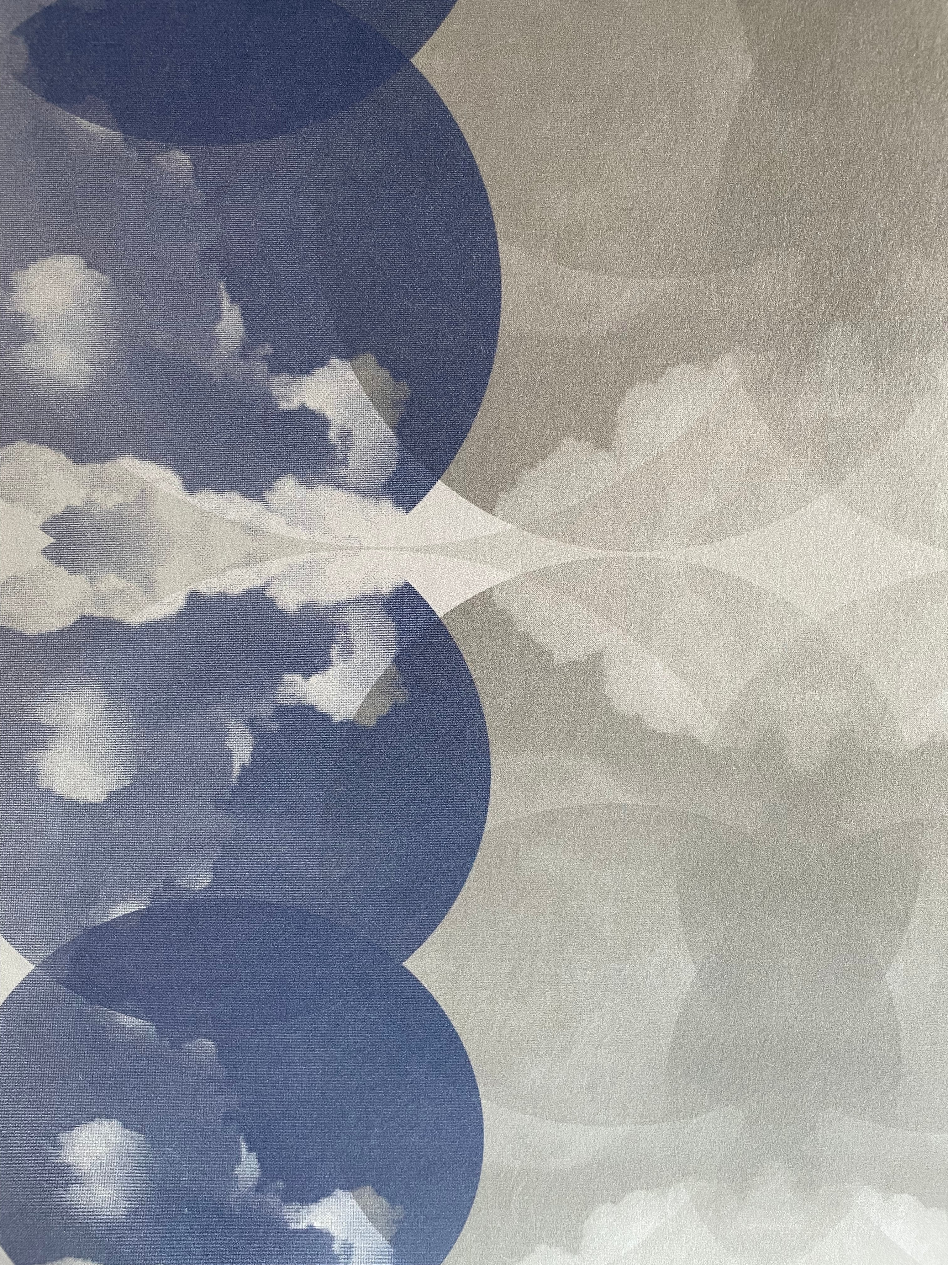 Close-up of wallpaper in a cloudy ink blot print in shades of blue and gray on a cream field.