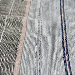 Close-up of a piece of woven fabric made with stripes of bulk yarn in shades of black, white, navy and pink.