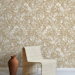 A straw chair and clay pot stand in front of a wall papered in a painterly wave print in white and light brown.