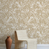 A straw chair and clay pot stand in front of a wall papered in a painterly wave print in white and light brown.