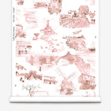 Partially unrolled wallpaper yardage in a playful illustrated city print in pink, brown and white.