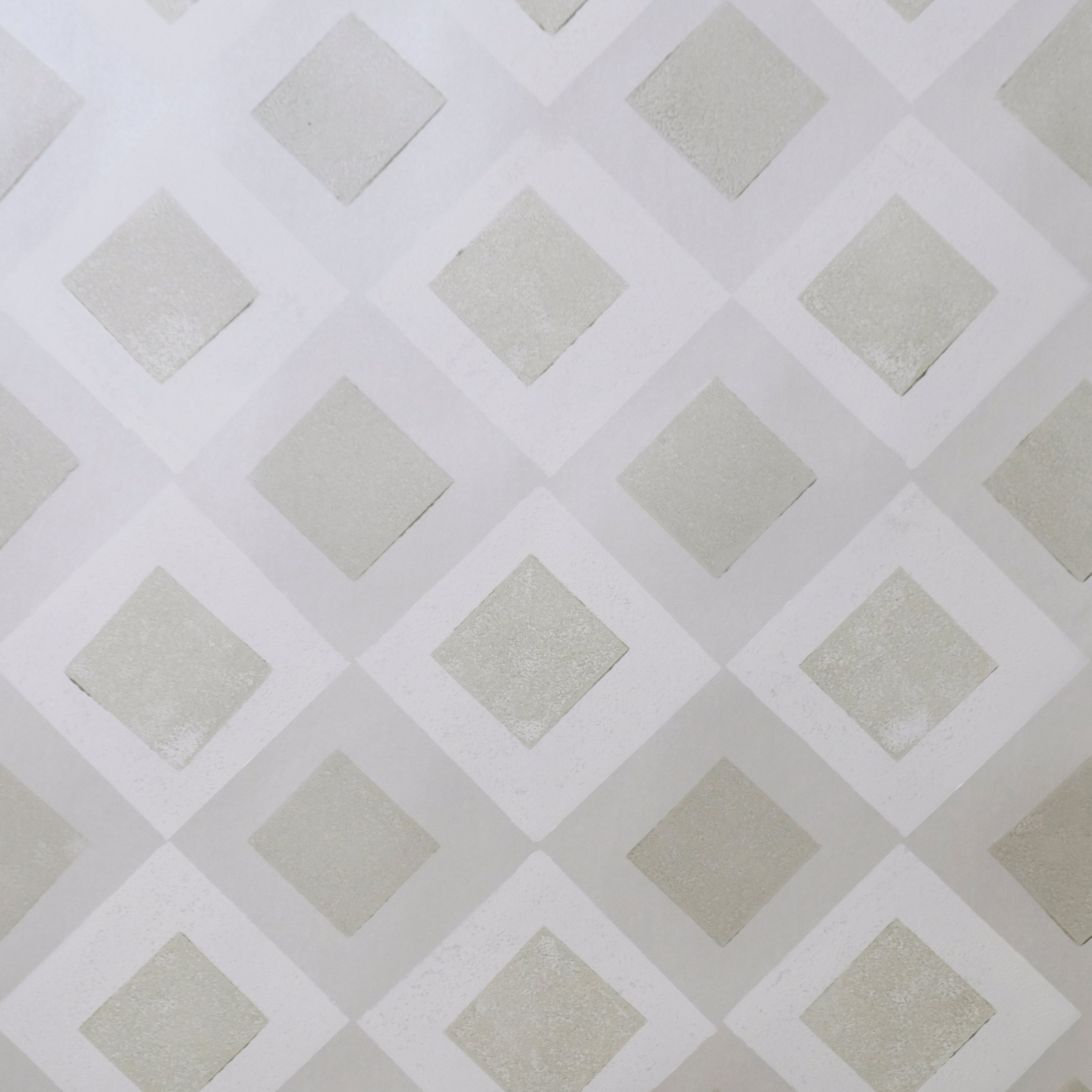 Detail of wallpaper in a diamond lattice print in shades of cream and grey.