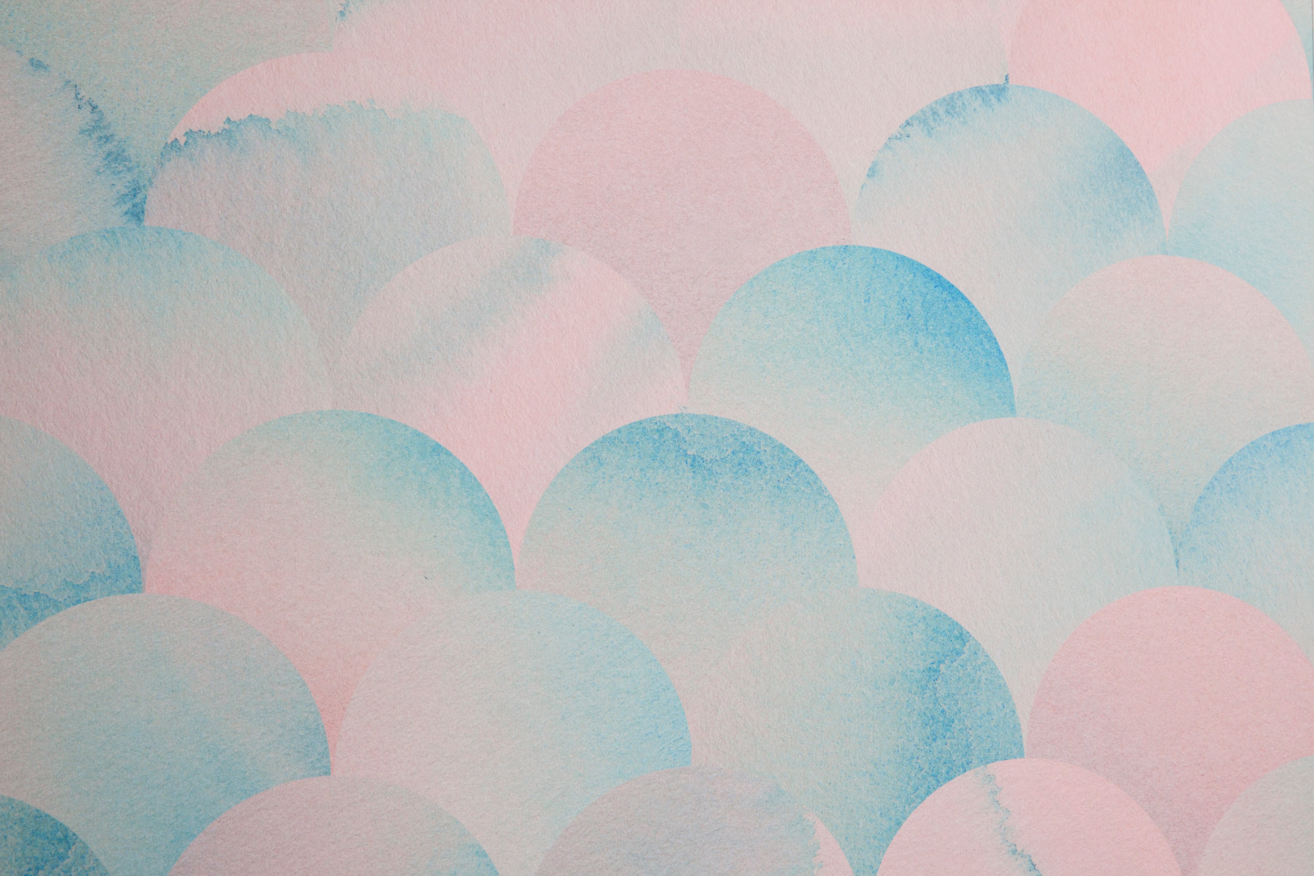 Detail of wallpaper in a repeating scalloped print in shades of blue and pink.