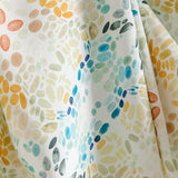 Draped fabric yardage in a painterly grid print in shades of blue, gray, and orange on a cream field.