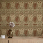 A table with a vase and cups stands in front of a wall papered in a floral damask print in cream, brown and sage.