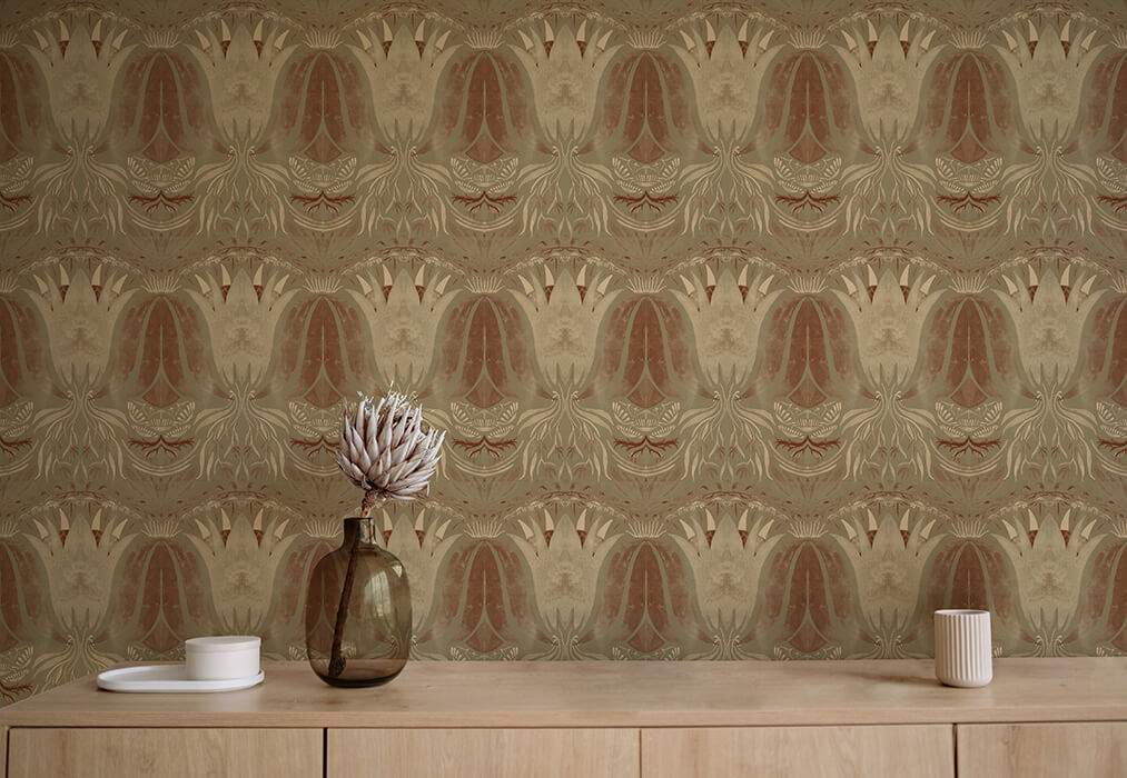 A table with a vase and cups stands in front of a wall papered in a floral damask print in cream, brown and sage.