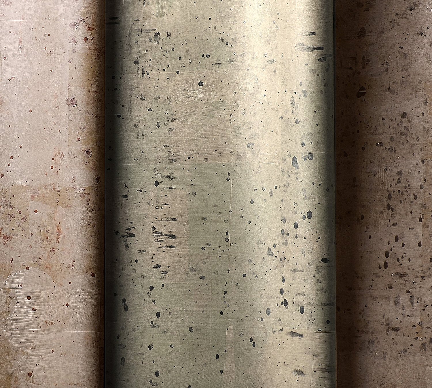 Three rolls of wallpaper in a row. Each has a delicate splatter print and a metallic finish in copper, silver or bronze.