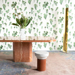 A modernist living tableau with a wall papered in a playful palm tree print in shades of green on a white field.