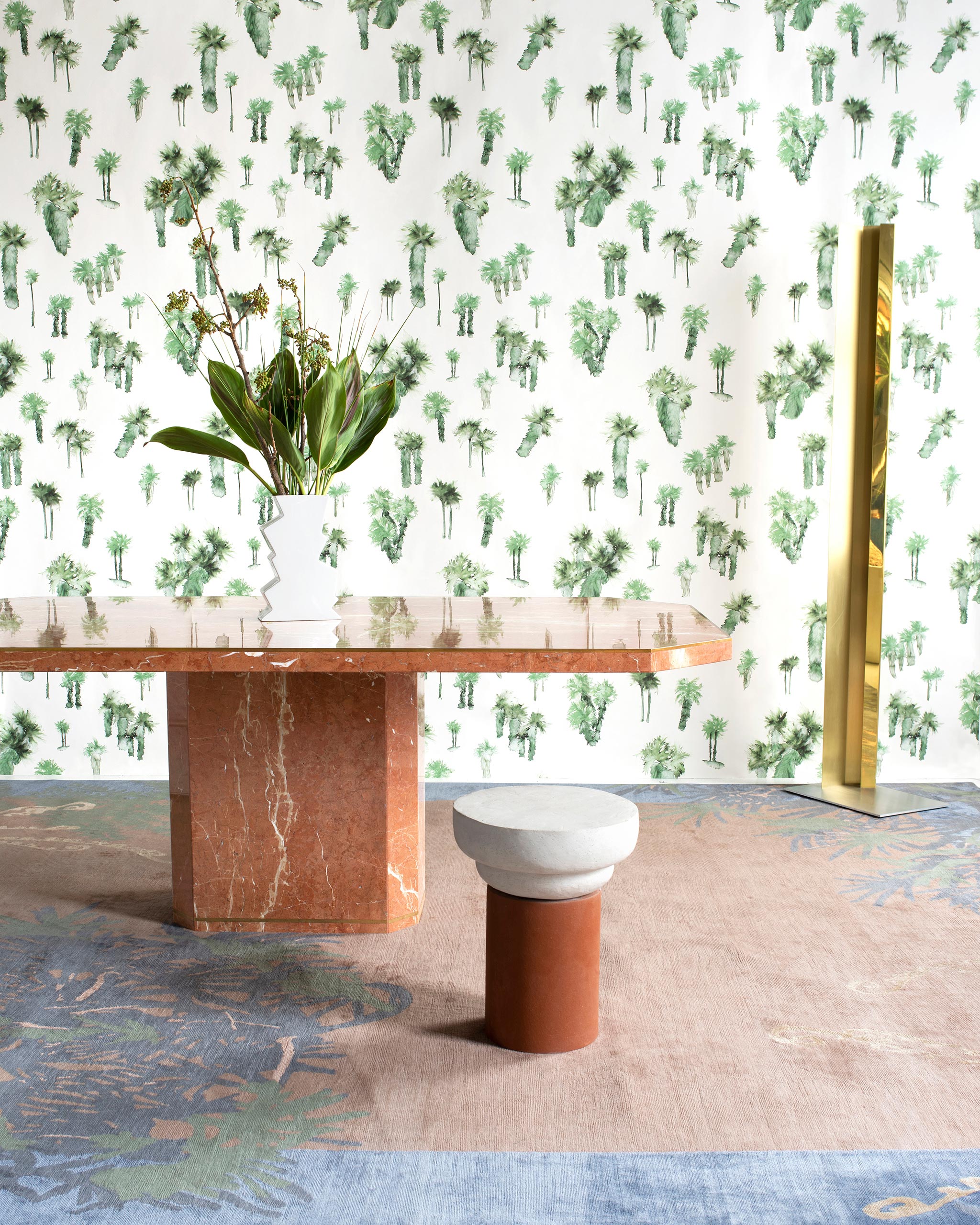 A modernist living tableau with a wall papered in a playful palm tree print in shades of green on a white field.