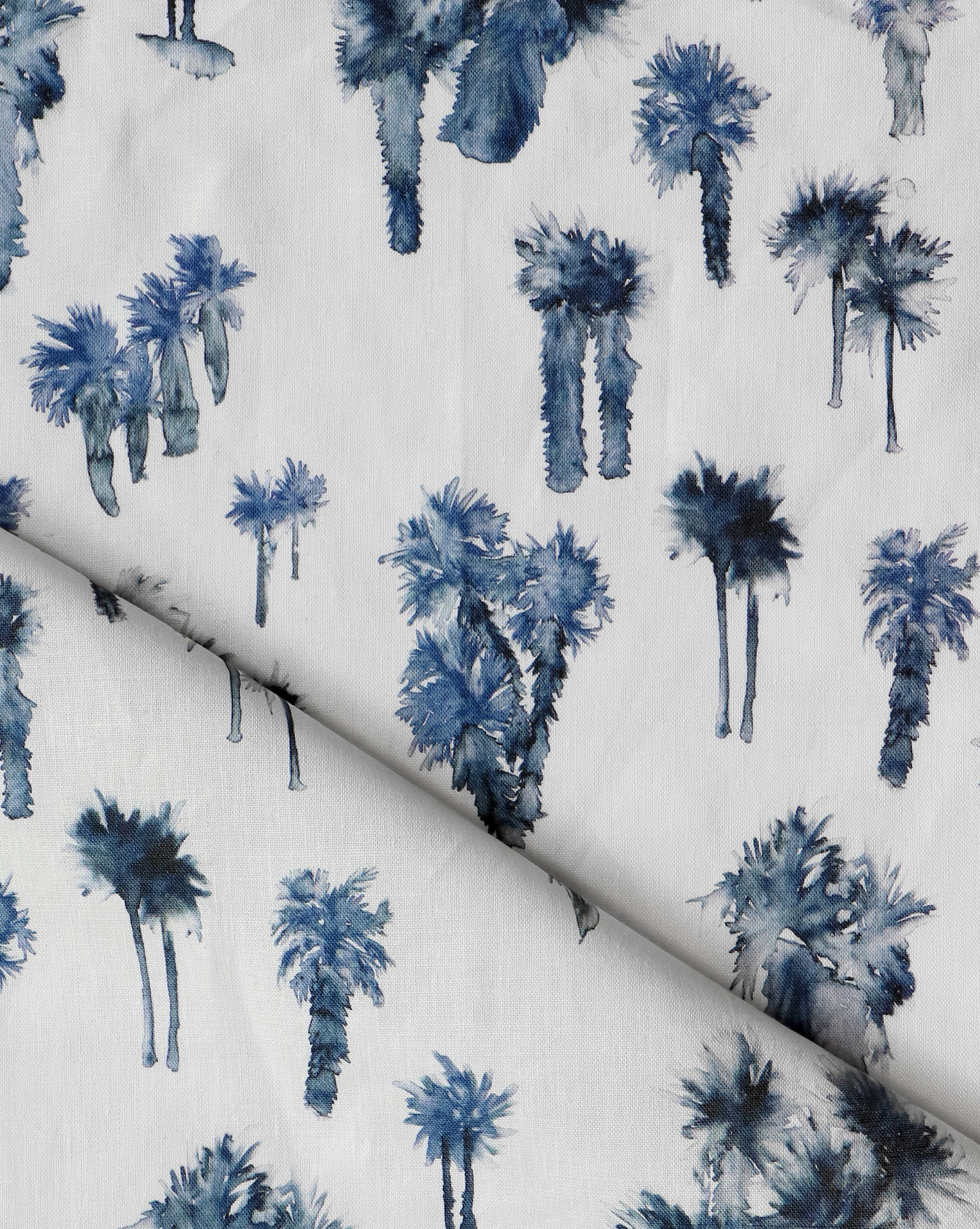 Draped fabric yardage in a painterly palm tree print in shades of navy on a white field.