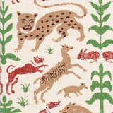 Detail of fabric in a playful animal and botanical print in brown, red and green on a white field.