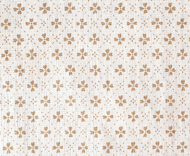 Detail of fabric in a dainty floral lattice print in tan on a cream field.