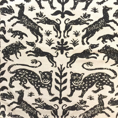 A cream wallpaper swatch with a block-printed repeat pattern of tigers, animals and leaves in black ink.