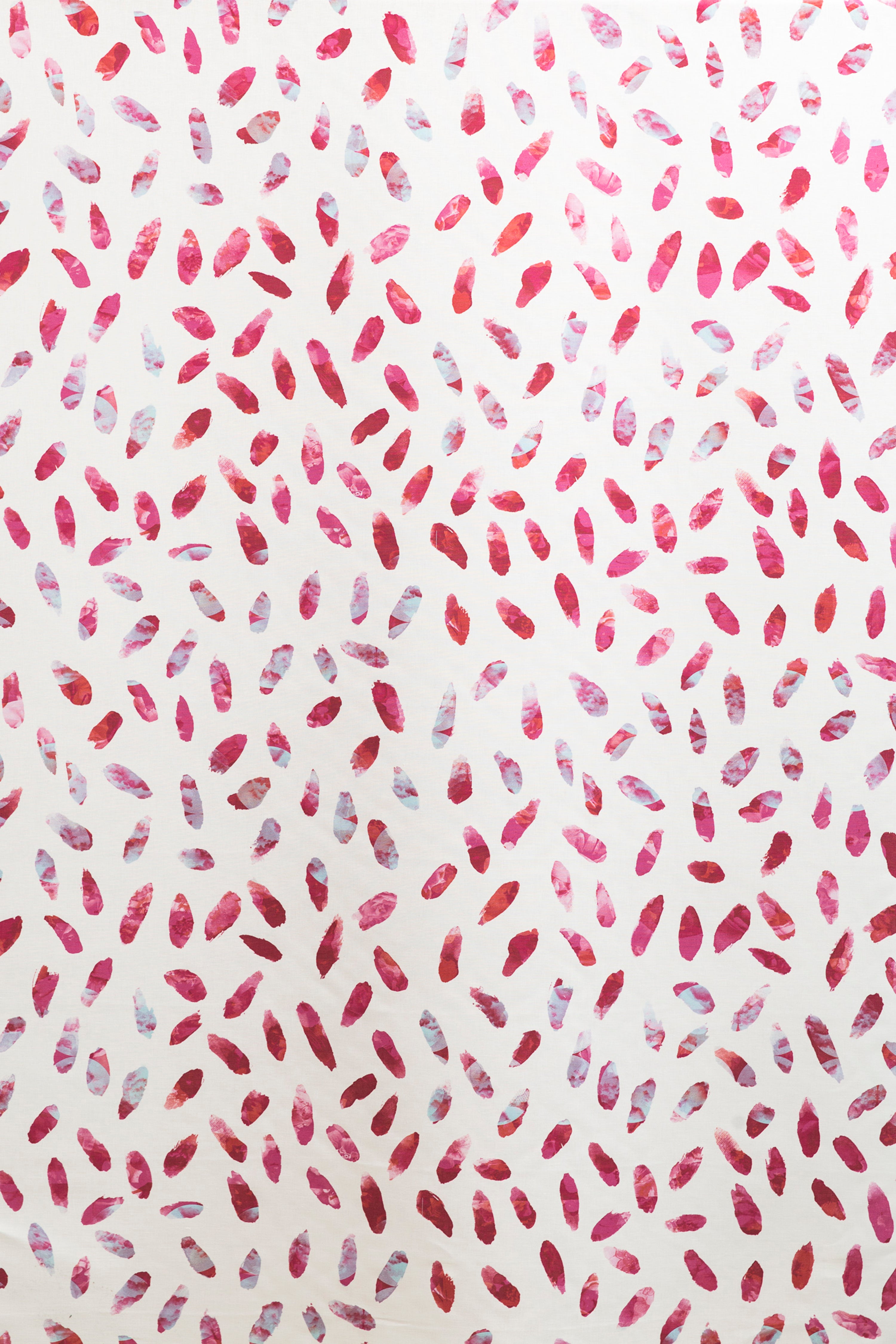 Detail of fabric in a playful paint blotch print in shades of pink and turquoise on a white field.