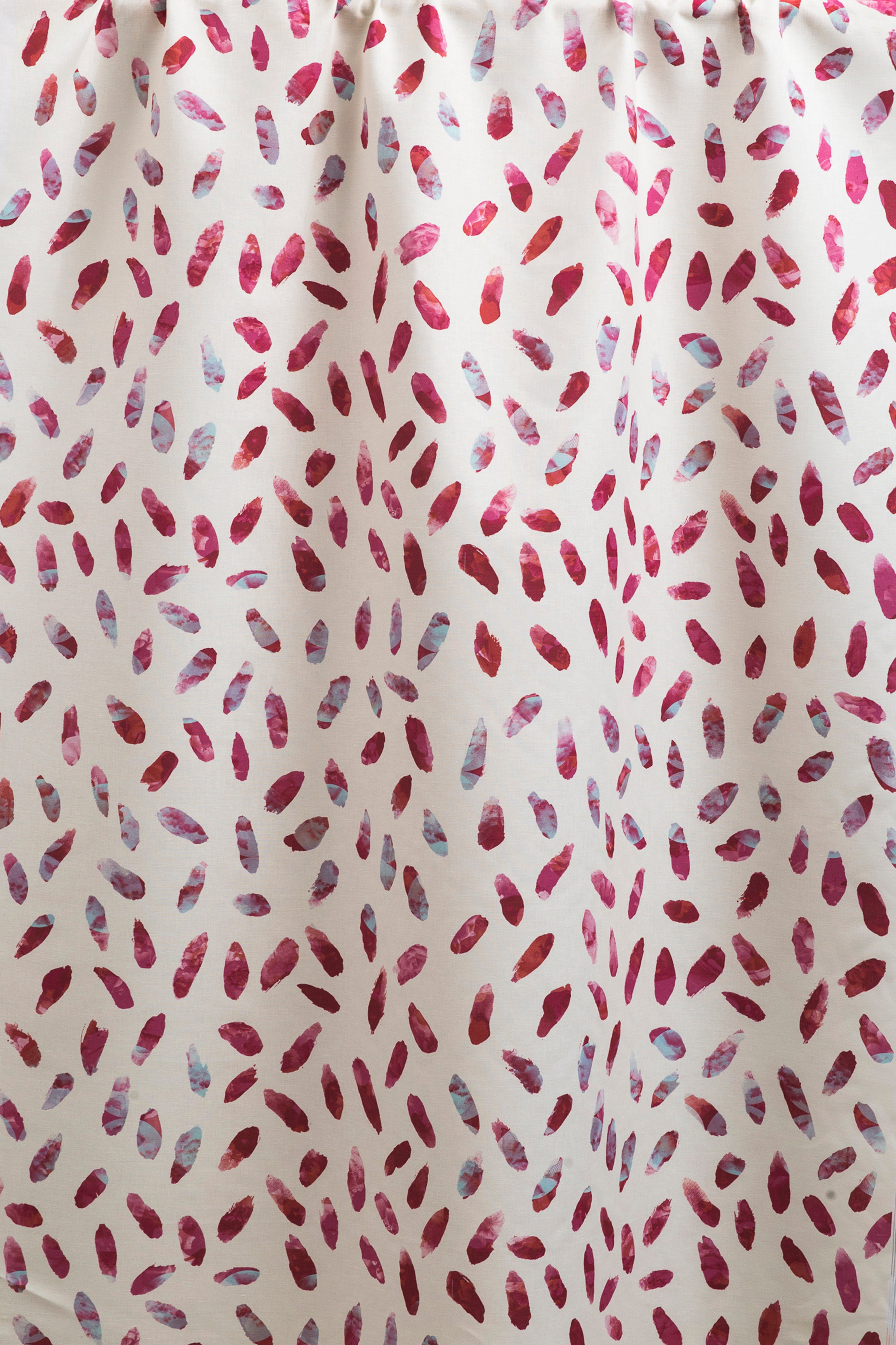 Draped fabric yardage in a playful paint blotch print in shades of pink and turquoise on a white field.