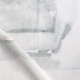 Draped fabric yardage in an abstract watercolor print in shades of gray on a white field.