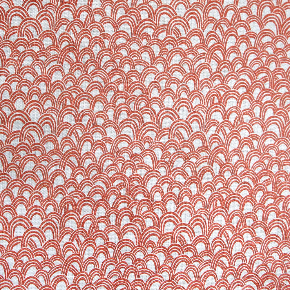 Detail of fabric in a playful repeating hoop pattern in coral on a cream field.