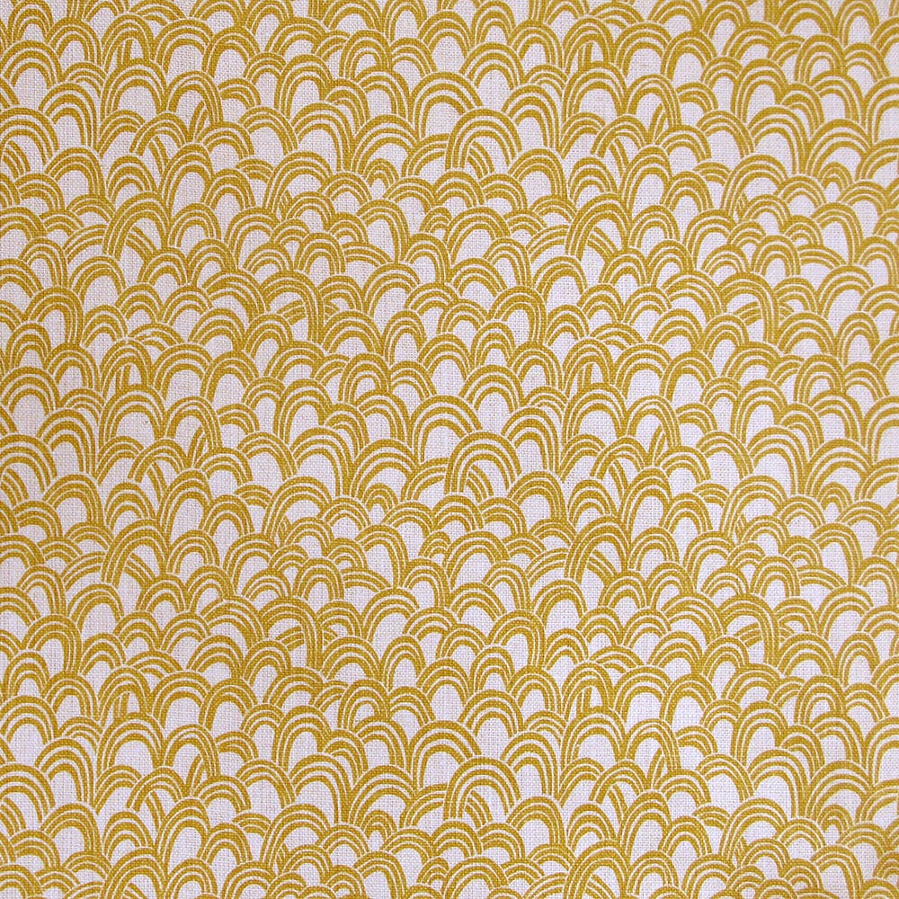 Detail of fabric in a playful repeating hoop pattern in mustard on a cream field.