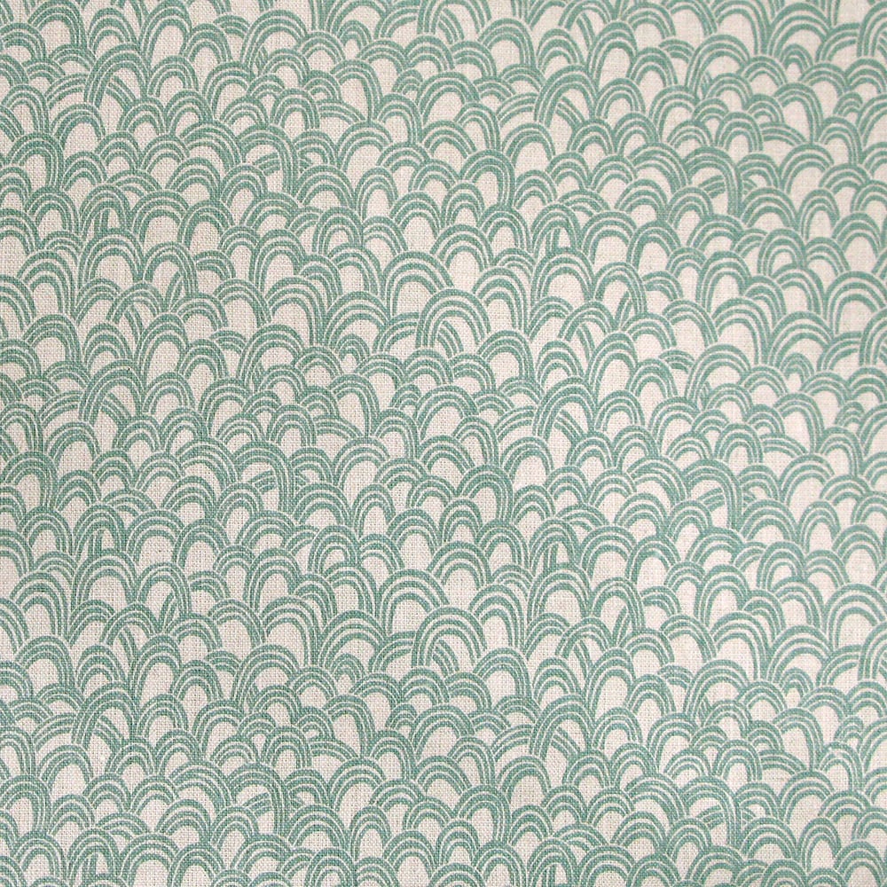 Detail of fabric in a playful repeating hoop pattern in turquoise on a cream field.