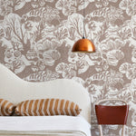 A modernist bed, hanging lamp and chair stand in front of a wall papered in a playful reef print in tan and white.