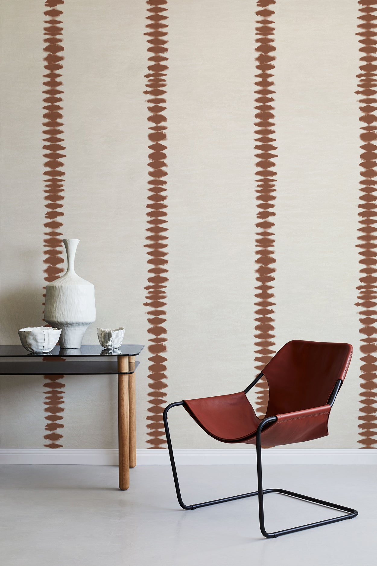 Modern interior with a red chair, black table, and decorative vase against a wall with abstract brown stripe