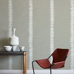 Modern interior with a red chair, table, and decorative items against a gray wall with white stripe pattern.