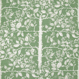 Detail of fabric in a large-scale tree and leaf print in cream on a green field.