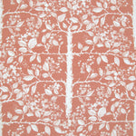 Detail of fabric in a large-scale tree and leaf print in clay pink on a green field.