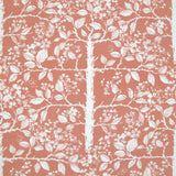Detail of fabric in a large-scale tree and leaf print in clay pink on a green field.