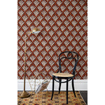 A chair and floor lamp in front of a wall papered in a repeating Moroccan-inspired scallop pattern in white and red on a maroon background.