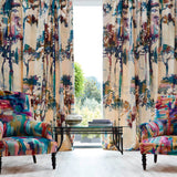 A living space with colorful armchairs and curtains upholstered in a painterly tree print.